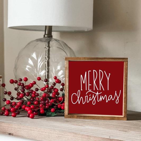 Merry Christmas sign with a cranberry red background and white font.
